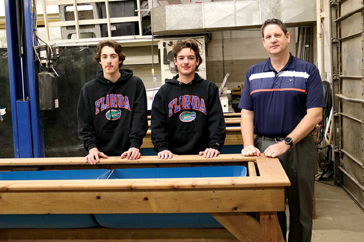 Grade 12 students Porter Skulmoski and Zayn Leslie, and Councillor Murray Gray beside raised planter boxes the students made for Moosomins community garden.